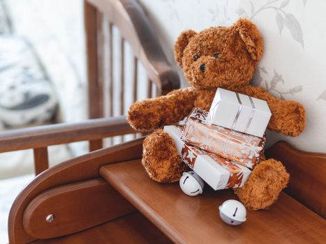 Teddy bear in kids room before New Year.. Plush toy with Christmas presents wrapped in white and golden paper.