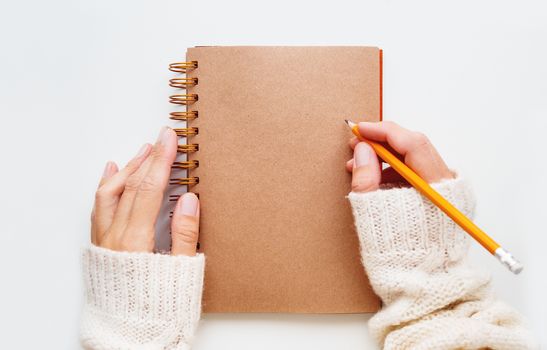 Woman is preparing to write or draw something in notepad with craft paper pages.