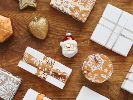 Christmas presents on shabby wooden background. New Year gifts in white and golden paper with bright ribbons.