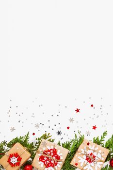 Christmas and New Year background with thuja branch, decorations and presents wrapped in craft paper with snowflakes. Flat lay, top view. Place for text.