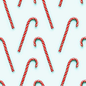 Seamless pattern of Christmas candy cone on light cyan background. Colorful holiday sweet lollipop. Dessert wtih red and white stripes.