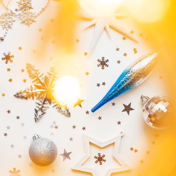 Christmas and New Year holiday background with decorations and light bulbs. Silver and blue shining balls, white snowflakes and star confetti. Flat lay, top view.