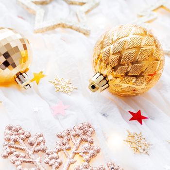 Christmas and New Year holiday background with decorations and light bulbs. Golden shining balls, snowflakes and star confetti.
