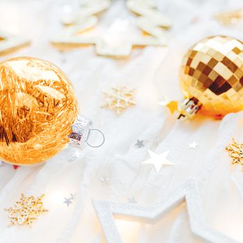 Christmas and New Year holiday background with decorations and light bulbs. Golden and transparent shining balls, snowflakes and star confetti.
