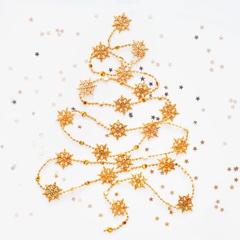 Christmas Tree made of golden snowflake garland with silver star confetti. New Year symbol with place for text. Flat lay, top view.