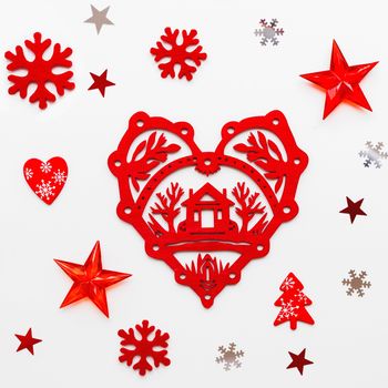 Christmas and New Year holiday background with decorations. Red heart with home symbol, snowflakes and star confetti. Flat lay, top view.