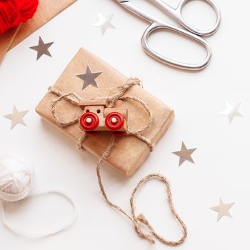 Christmas and New Year DIY presents in craft paper. Holiday gifts tied with white and red threads with toy train as decoration.