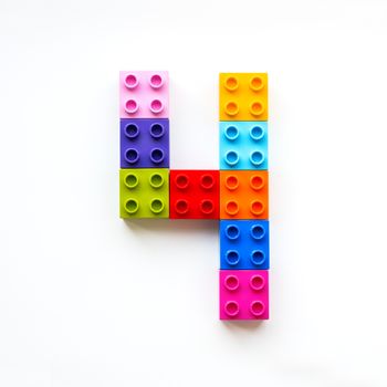 Number Four made of colorful constructor blocks. Toy bricks lying in order, making number 4. Education process - learning numbers with child using multicolored toy details.