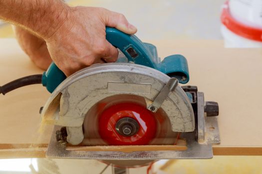 Carpenter using hands cutting wood with electric saw