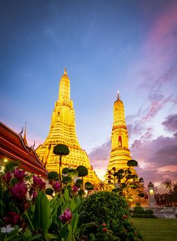 Wat Arun Ratchawararam at sunset with beautiful dark blue sky and clouds. Wat Arun buddhist temple is the landmark in Bangkok, Thailand. Attraction art and ancient architecture in Bangkok, Thailand.