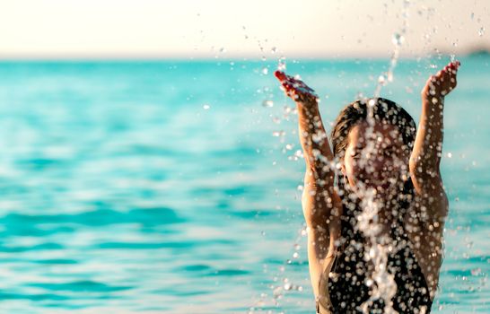 Happy young Asian woman in black swimsuit relax and enjoy holiday at tropical paradise beach. Girl in summer vacation splash water in the sea. Sexy model. Sexy woman in black bikini. Summer vibes.   