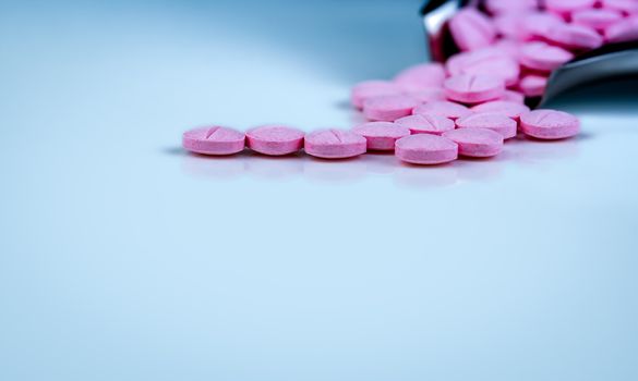 Pink tablets pills on blurred background of drug tray. Pharmaceutical industry. Pharmacy products. Vitamins and supplements. Medication use in hospital or drugstore. Global drug retail market. 