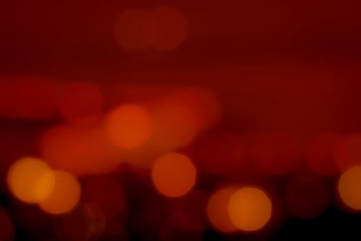 Blurred red and orange bokeh background. Blur abstract background of urban light. Warm light with beautiful pattern of round bokeh. Red light in the night. Street lamp blurred lights. Romantic night.