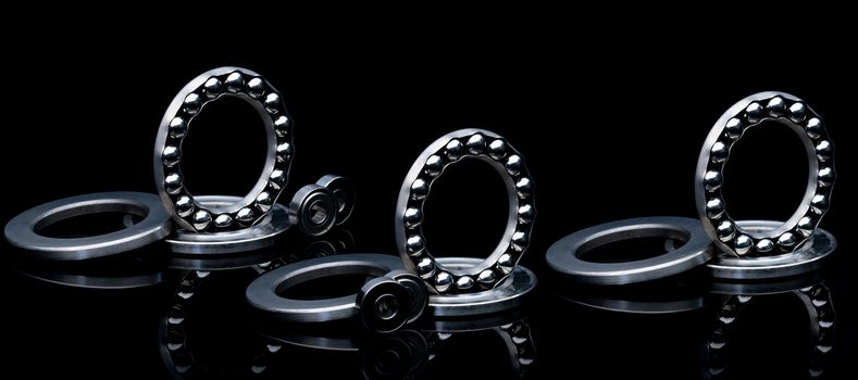 Stainless steel thrust ball bearing. Set of thrust ball bearing and shiny silver ball bearing. Spare parts for roller machine in heavy machinery and automotive industry. Round metal wheel. 