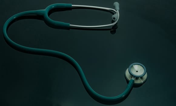 Green stethoscope on doctor table or nurse desk. Health checkup or health insurance concept. Cardiology doctor equipment. Medical healthcare background. Physician tool for patient diagnosis.