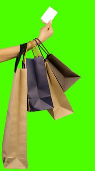 Woman consumer hand holding colorful shopping bag and credit card isolated on green background. Consumerism concept. Asian woman shopping and paying with credit card. Black Friday sale concept. 