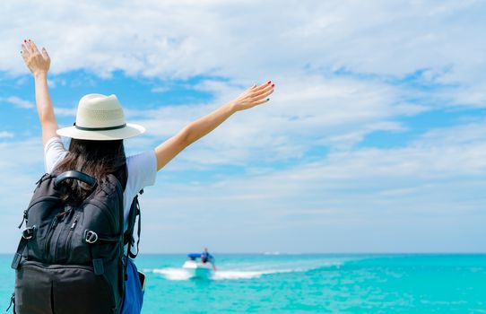 Happy young Asian woman in casual style fashion with straw hat and backpack. Relax and enjoy holiday at tropical paradise beach. Girl stand at the wood pier of resort in summer vacation. Summer vibes.