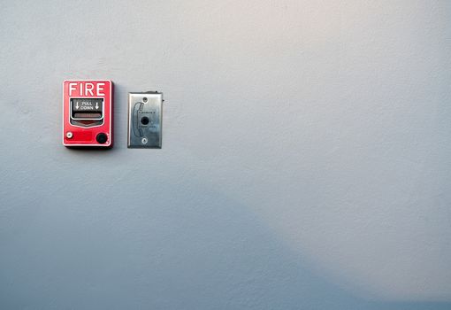 Fire alarm on white concrete wall. Warning and security system. Emergency equipment for safety alert. Red box of fire alarm on wall of school, hospital, factory, office, apartment, or home. Pull down.