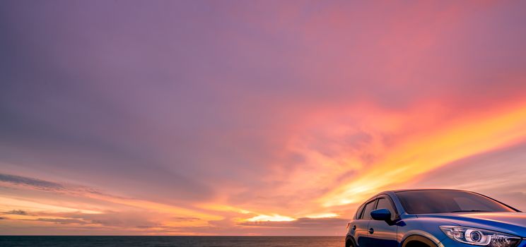 Blue compact SUV car with sport and modern design parked by beach at sunset. Hybrid and electric car technology. Car parking space. Automotive industry. Car care business background. Beautiful sky.