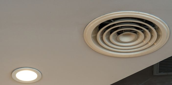 Air duct on ceiling in the mall or hospital. Air conditioner install on gypsum ceiling near ceiling lamp. Building interior concept. Air heading unit on gypsum wall. Cool system in the building. 