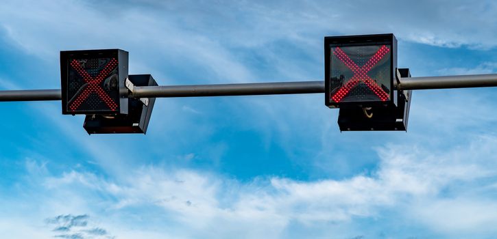 Traffic signal light with red color of cross sign on blue sky and white clouds background. Wrong sign. No entry traffic sign. Red cross guidance stop go traffic signal light. Warning traffic light. 