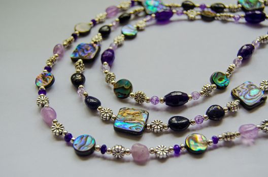 Close up view of necklaces handmade with abalone shell beads together with quartz, amethyst, marcasite and small silver plated beads.