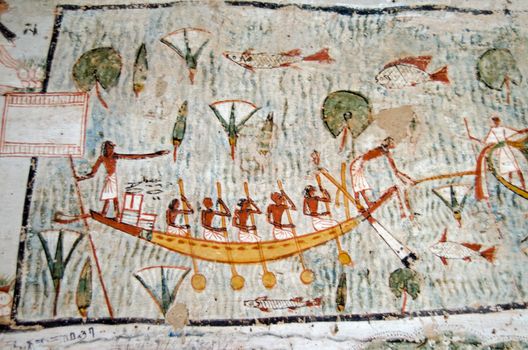 Ancient Egyptian mural on the wall of a tomb showing five oarsmen operating a rowing boat across a sacred lake awash with fish and lotus plants.  Historic painting in the tomb of Amenemonet a priest from the Ramesside Period, West Bank of the Nile at Luxor, Egypt.