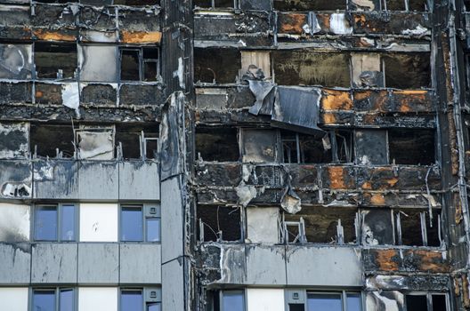 Close up view of the exterior of the Grenfell Tower block of flats in which at least 80 people lost their lives in a fire.  Remains of exterior cladding can be seen out the outside of the building, this is thought to have increased the spread of the fire.