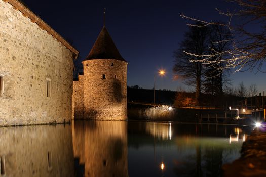 Schloss Hallwil, castle in Switzerland at night with reflection in river.