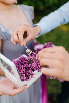 the groom dresses the bride with wedding rings near the lilac arch