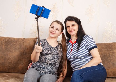 mom and daughter take selfie with smartphone while sitting on the sofa at home. coronavirus quarantine.