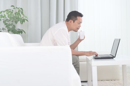 Modern asian man working remotely from home,drinking coffee  during Coronavirus pandemic in the world.