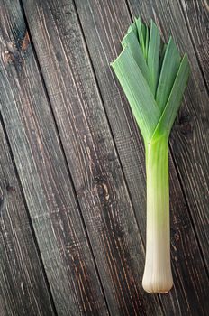 Leek on wooden background top view. Free space.