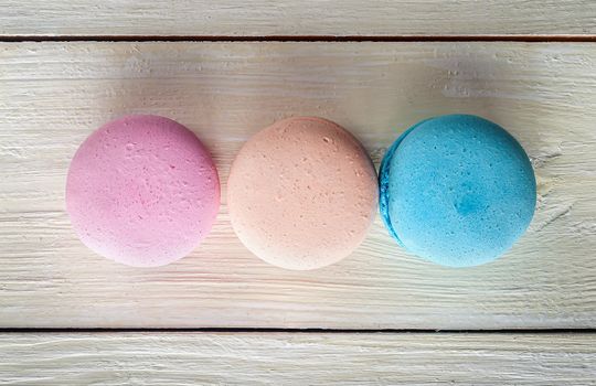 Three macaroons in a row on wooden background top view