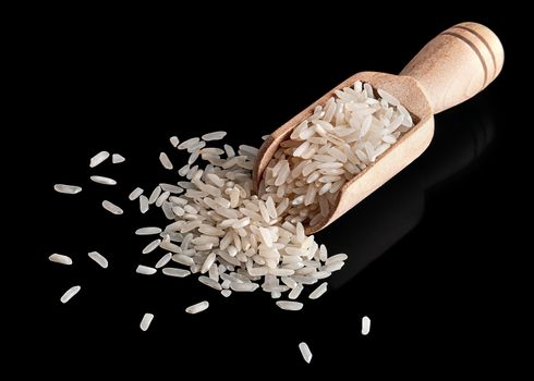 White rice in wooden scoop on black background