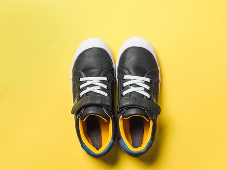 pair of new kids or adult sneakers on yellow background, top view. Flat lay gray and yellow or mustard color sneakers shoes on colorful bright background with copy space for text or design