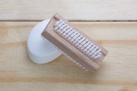 A top view of traditional nail brush and soap bar on wooden surface