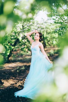 brunette girl in a turquoise dress walking in the spring garden