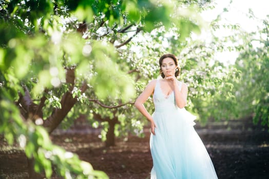 brunette girl in a turquoise dress walking in the spring garden