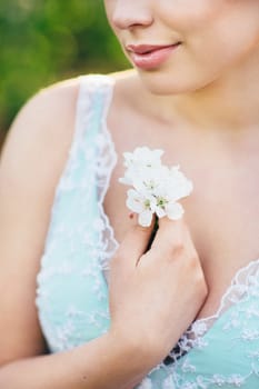 brunette girl in a turquoise dress walking in the spring garden