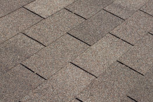 A background image of shingles on a house roof showing their texture, pattern and brown color.