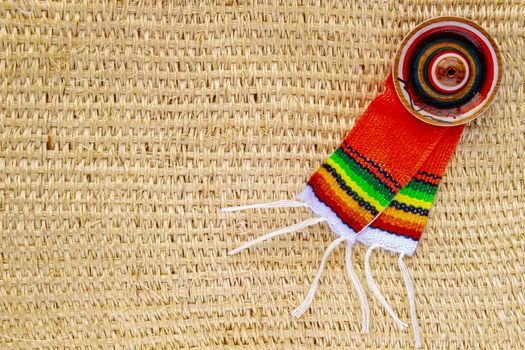 Cinco de Mayo background. A Poncho and a sombrero on a straw rural bag background texture