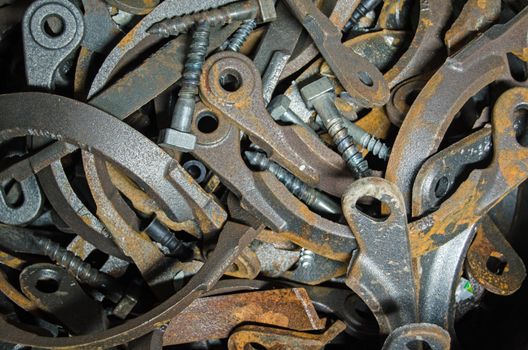 View of a pile of brackets and bolts quietly rusting in a bucket beside a civil engineering project.