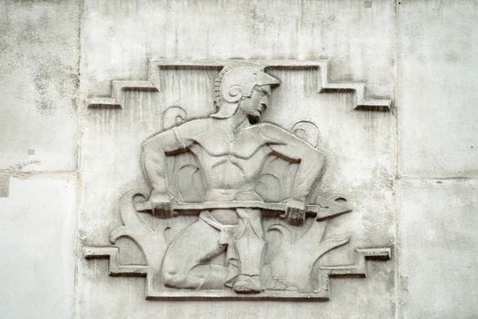 Sculpted stone relief of the Roman god of fire Vulcan.  On the facade of the 1930's building which once house the headquarters of the British Iron and Steel Federation on Tothill Street, Westminster, London.  Sculpted in Portland stone by William Aumonier junior.  Viewed from public road.