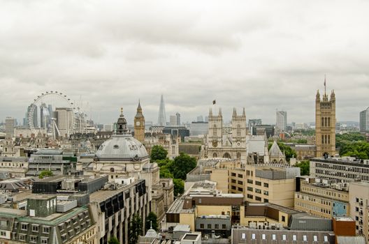 View across the rooftops of Westminster looking towards Westminster Abbey, Methodist Central Hall, the Houses of Parliament and across the river to Southwark and The Shard and other tall buildings. Cloudy summer day.