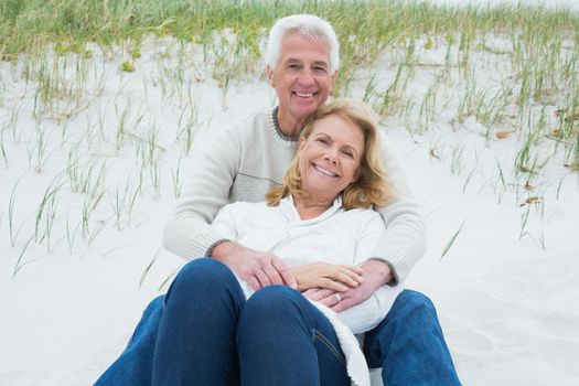 Romantic senior man and woman relaxing on sand at the beach