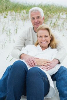 Romantic senior man and woman relaxing on sand at the beach