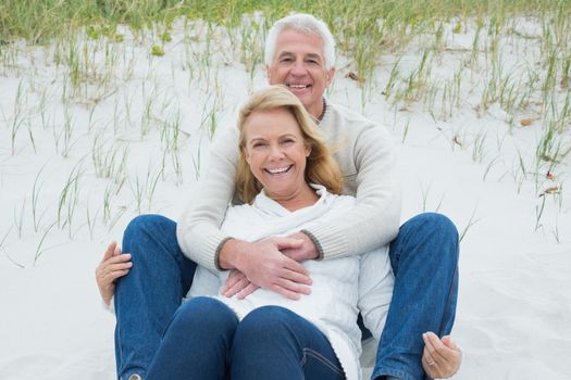 Romantic senior man and woman relaxing on sand at the beach