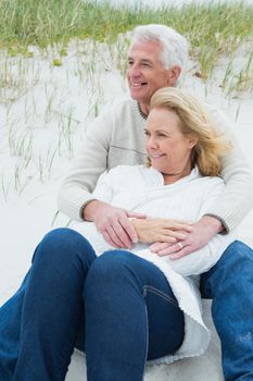 Romantic senior man and woman relaxing on sand at the beach