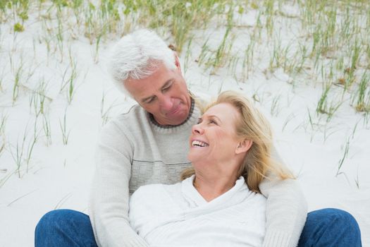 Romantic senior man and woman relaxing on sand at the beach